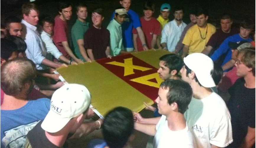 Delta Chi members gathered around the chapter flag